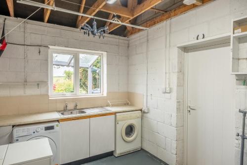 a kitchen with a washing machine and a sink at Spring Cottage in Burnham Market