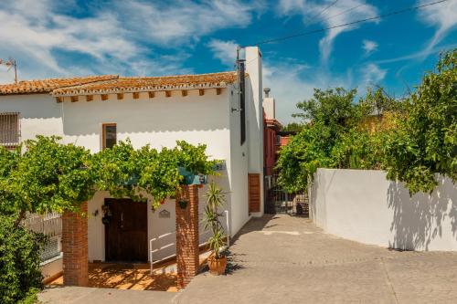 een wit huis met een poort en bomen bij Rocamadour Casa del Caminito in Málaga