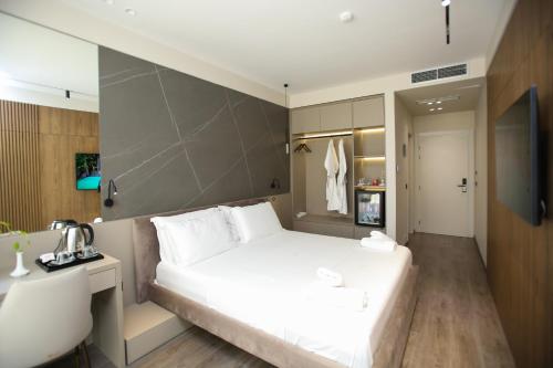 a bedroom with a large white bed and a desk at Charm Hotel in Vlorë