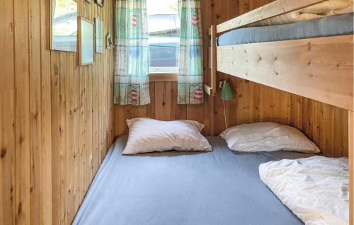a bed with two pillows in a wooden room at Lovely Home In Nordtveitgrend With House Sea View in Haugen