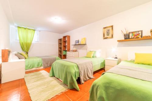 2 Betten in einem Zimmer mit grüner Bettwäsche in der Unterkunft Villa dos Narcisos in Aroeira