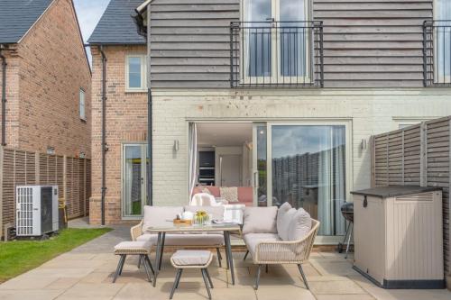 a patio with a table and chairs in front of a house at Kingfishers Cove in Titchwell