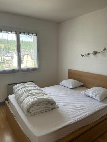 una camera da letto con un letto con lenzuola bianche e due finestre di Le clouquié a Espalion