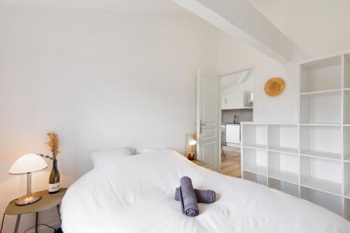 Un dormitorio con una cama blanca con un osito de peluche púrpura. en Appartement climatisé 2 chambres en Villefranche-sur-Saône