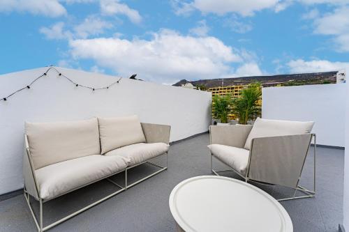 a patio with two chairs and tables and a white wall at 2BDR Ocean View & Large PRIVATE Terrace in Puerto de Santiago in Puerto de Santiago