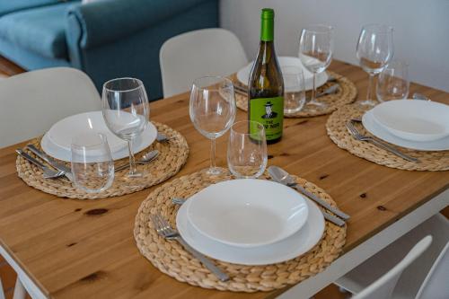 a wooden table with white plates and wine glasses at 2BDR Ocean View & Large PRIVATE Terrace in Puerto de Santiago in Puerto de Santiago