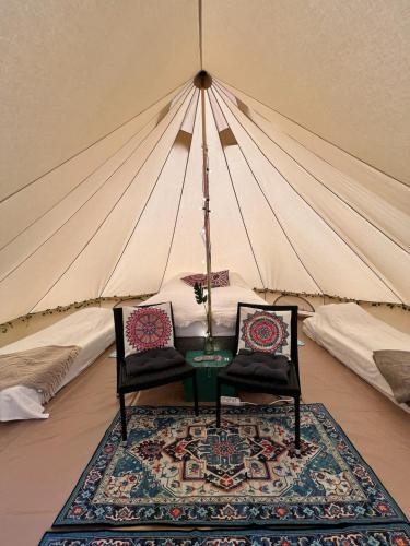 a tent with two chairs and a table and a rug at Hommen Gård Glamping in Risør