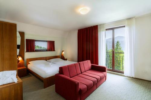 une chambre d'hôtel avec un lit et un fauteuil rouge dans l'établissement Beltine Forest Hotel, à Ostravice