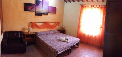 a bedroom with a bed and a chair and a window at Dirindello House Trasimeno in Magione