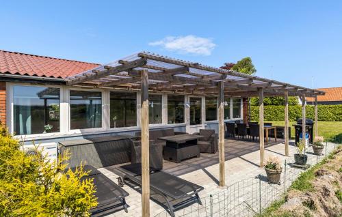 a pergola on a patio with a table and chairs at 3 Bedroom Beautiful Home In Rønne in Rønne