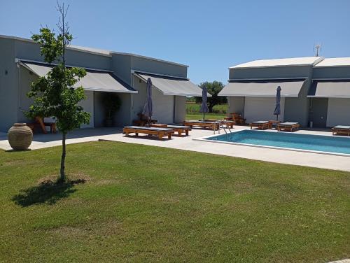 un bâtiment avec une piscine, des tables de pique-nique et un arbre dans l'établissement Olympia Suites, à Pyrgos