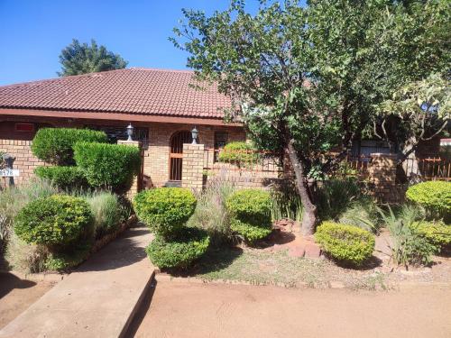una casa con arbustos y un banco delante en Ditshane Lodge, en Gaborone