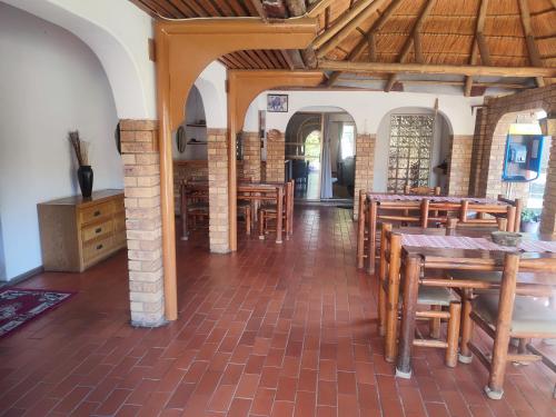 Un comedor con mesas y sillas de madera. en Ditshane Lodge, en Gaborone