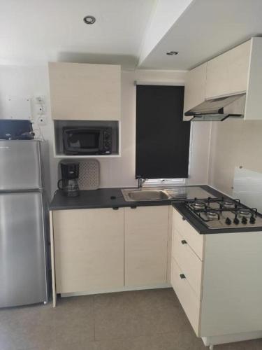 une cuisine avec des armoires blanches et des appareils en acier inoxydable dans l'établissement Charmant mobil-home 98, à Narbonne