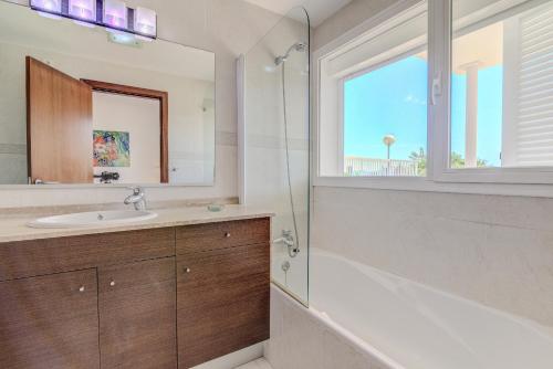 a bathroom with a tub and a sink and a window at Villa Vistafar by Rentallorca in Alcudia