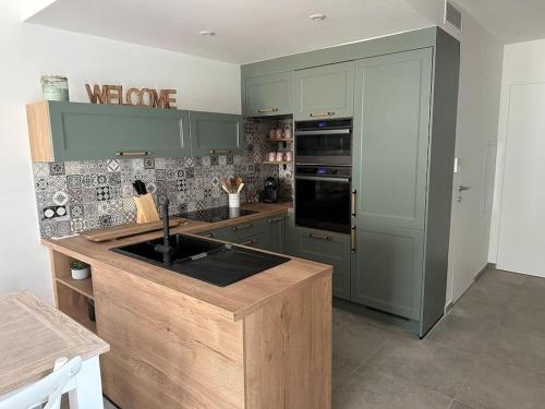 une cuisine avec des placards verts et un comptoir dans l'établissement Duplex avec piscine, près de la mer, Cala Rossa, à Lecci