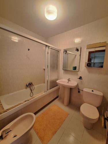 a bathroom with a sink and a toilet and a bath tub at Piso da Playa in Laxe