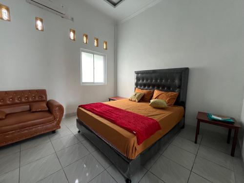 a bedroom with a bed and a couch in it at Guesthouse Ananda Lubuk Basung in Ambacauggatal