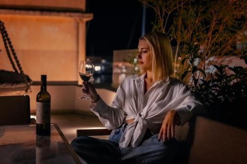 a woman sitting on a couch holding a glass of wine at Ninemian Suites Syros in Ermoupoli