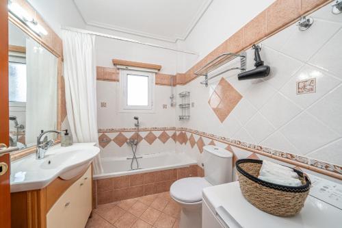 a bathroom with a toilet and a sink and a tub at Arte villa Margarita apartment in Karavomylos
