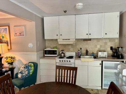 a kitchen with white cabinets and a table and chairs at Westhampton Seabreeze Motel in Westhampton