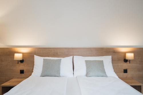 a bedroom with a white bed with two pillows at Hotel Brocco & Posta in San Bernardino