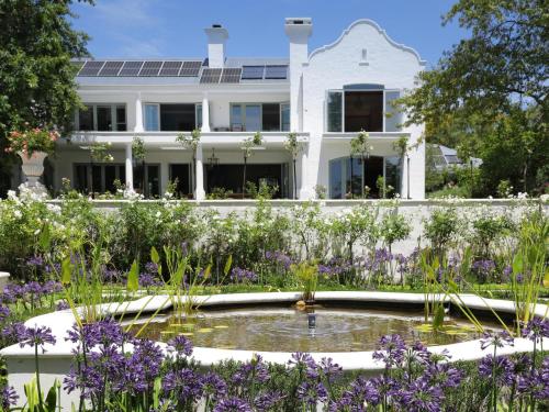 a garden with a pond in front of a white house at Constantia Klein in Cape Town
