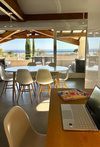 un ordinateur portable assis sur une table avec des chaises dans l'établissement Villa provençale avec vue mer, proche centre ville et plages., à Saint-Raphaël