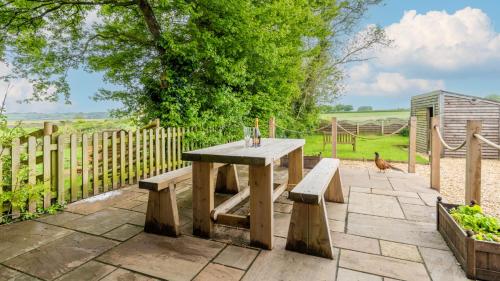 een houten picknicktafel en banken in de tuin bij Old Stables, Little Ballthorns Farm in Cold Ashton