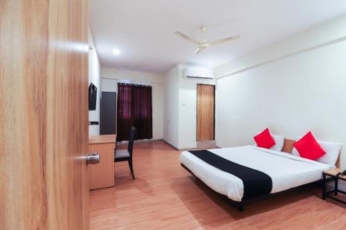 Schlafzimmer mit einem Bett mit roten Kissen und einem Schreibtisch in der Unterkunft Capital O 71317 White Ridge in Hyderabad