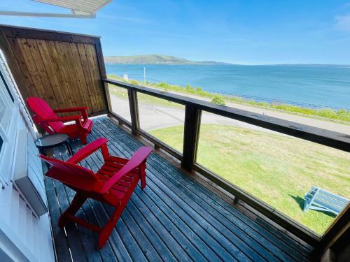2 rote Stühle auf einer Terrasse mit Meerblick in der Unterkunft Admiral Digby Inn Restaurant and Cottages in Digby