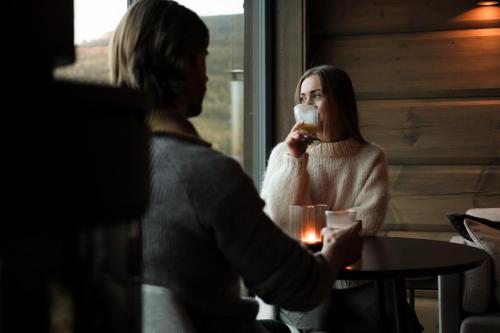 een vrouw die een glas wijn drinkt naast een man bij Unique Romantic Cabin with Mountain View at Strandafjellet, Mivo X in Stranda
