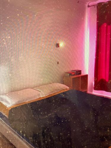 Cette chambre comprend un lit avec un mur rose. dans l'établissement Appartement ensoleillé, calme rue Jonquoy, 14e arrondissement, à Paris