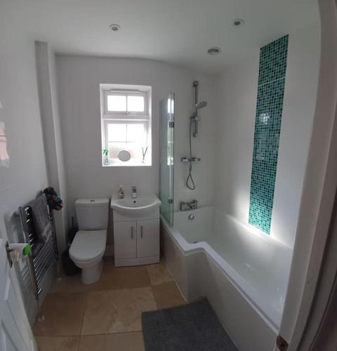 a bathroom with a toilet and a tub and a sink at Arundel Central Apartment with parking in Arundel