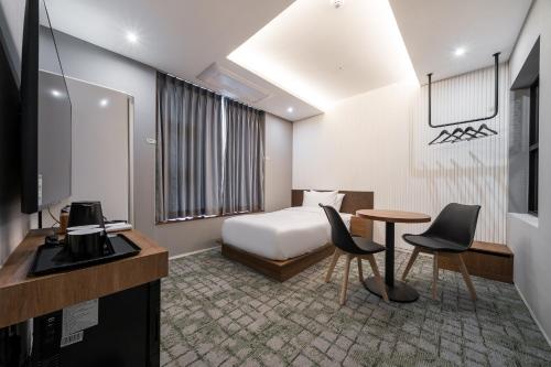 a hotel room with a bed and a table and chairs at Hotel Haedeun in Sokcho