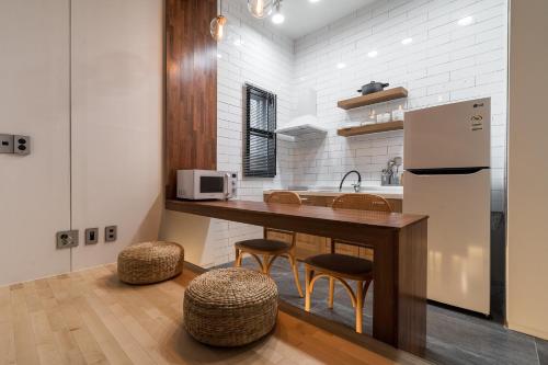 a kitchen with a counter and a refrigerator and stools at Hotel Haedeun in Sokcho