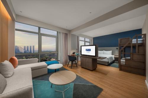 uma sala de estar com um sofá, uma cama e uma televisão em Holiday Inn Express Beihai Silver Beach, an IHG Hotel em Beihai