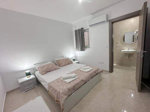 a white bedroom with a bed and a sink at AP Central Swieqi in Is-Swieqi