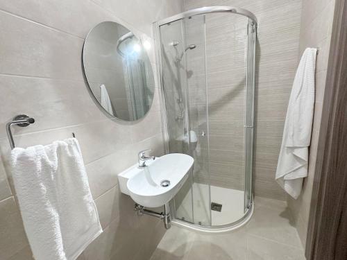 a white bathroom with a sink and a mirror at AP Central Swieqi in Is-Swieqi