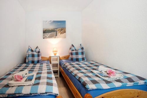 two twin beds in a small room with a table at Bungalow Netzboden, Bgl 28 in Dranske