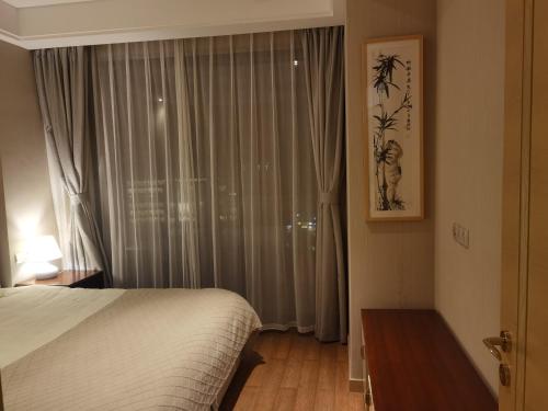 a bedroom with a bed and a window with curtains at Pinxiayuan Apartment in Lvcheng Resort in Zhoushan