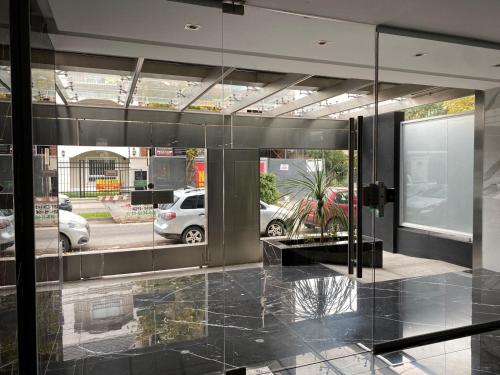 una hall con pareti in vetro e una macchina parcheggiata in un parcheggio di Adrogué Apartments, zona céntrica de Adrogué a Adrogué