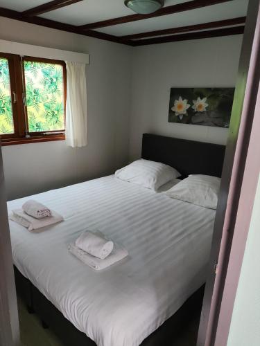 a bedroom with a large white bed with towels on it at Vakantiehuisje Veluwe, Alleen Voor Recreatie in Putten