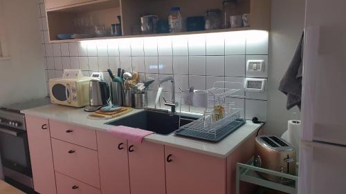 Gil's Home of Joy & Serenity في حيفا: مطبخ وردي مع حوض وميكروويف