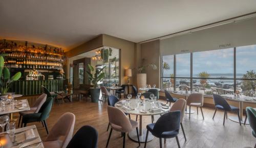 a restaurant with tables and chairs and windows at Salthill Hotel in Galway