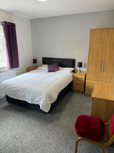 a bedroom with a large bed and a red chair at Merrick Lodge Hotel in Coventry