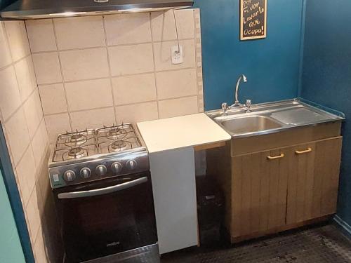 uma pequena cozinha com um fogão e um lavatório em Pies a tierra em Coihaique