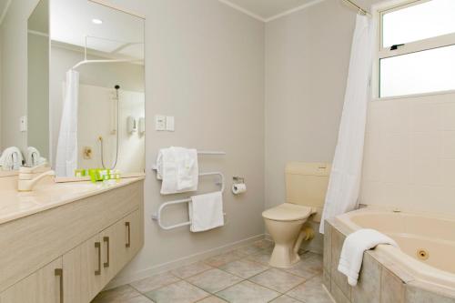 een badkamer met een bad, een toilet en een wastafel bij Anchorage Resort Taupo NZ in Taupo
