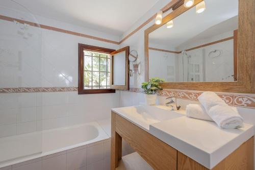 a bathroom with a sink and a tub and a mirror at Villa Can Cosme in Alcudia