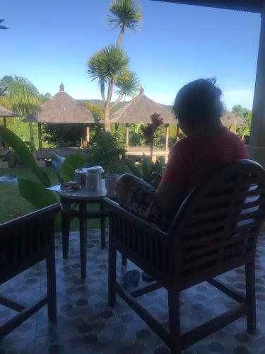 a woman sitting on a bench looking out at a patio at Wana house wanagiri munduk bali in Gitgit